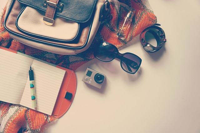 A tote bag, sunglasses, and a notebook placed on a table.