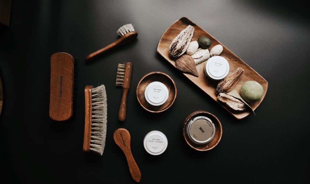 A set of leather wrist watch straps and brushes on a black surface.