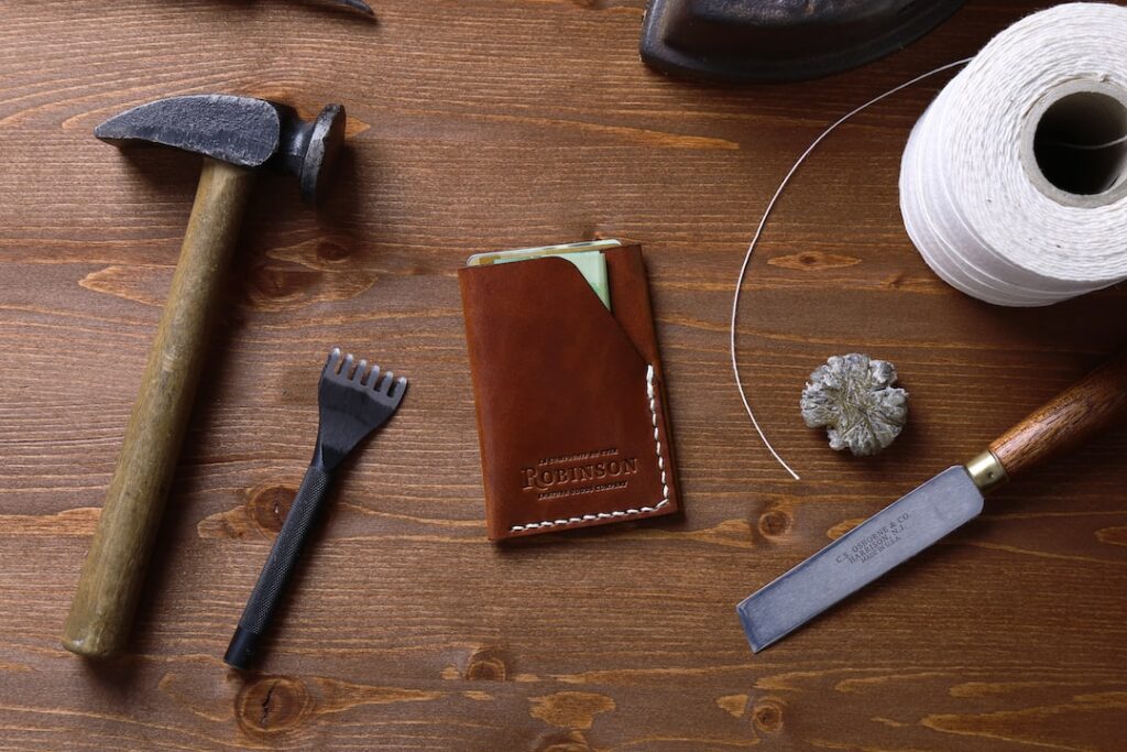 A wooden table with a few leather crafts kits.