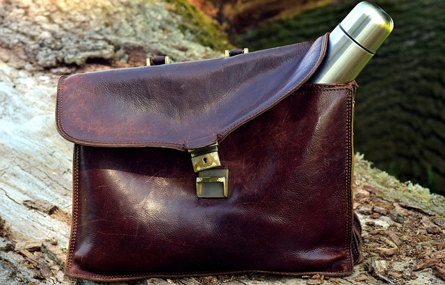 A brown leather attache case with a bottle of water on it.