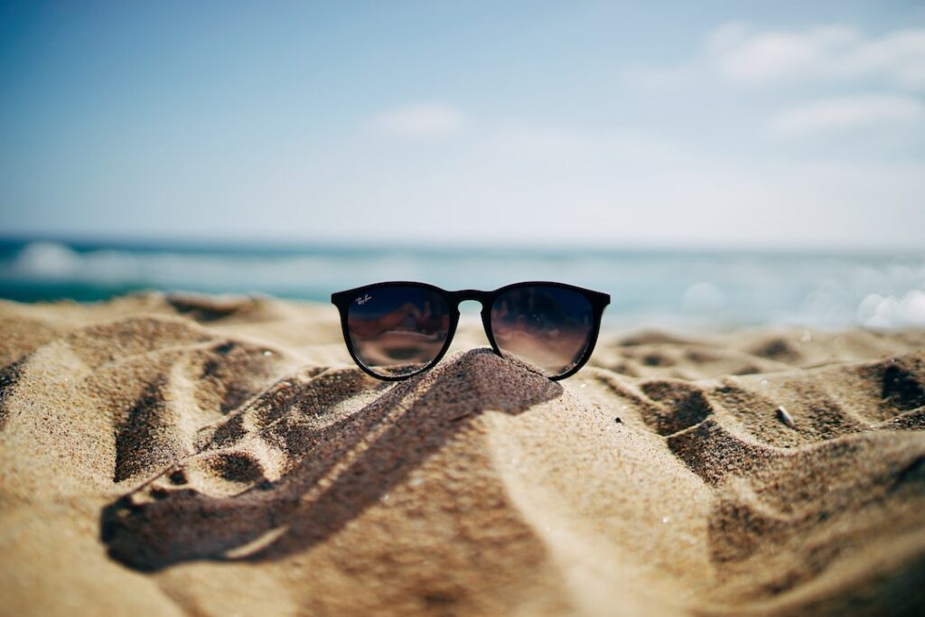 A pair of first-rate sunglasses sitting in the sand on a beach.