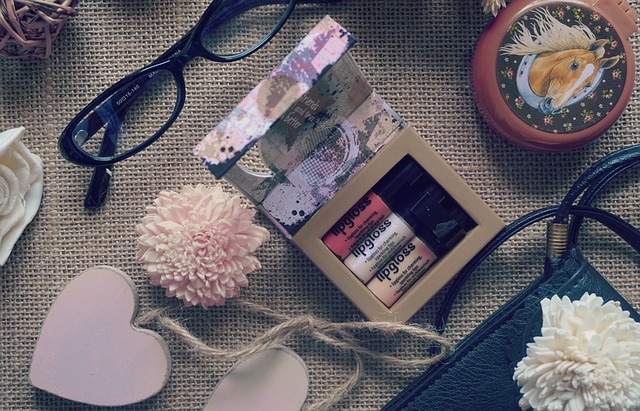 An outstanding collection of eyeshadow palettes, eyeglasses, and a purse on a table.