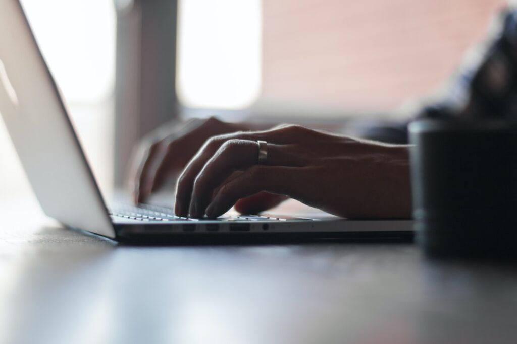 Perfect person typing on a laptop in front of a window.