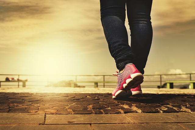 A woman is walking on a sidewalk in her leading sneakers.