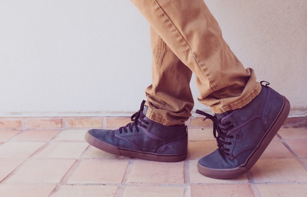 A person's legs are standing on a perfect tiled floor.
