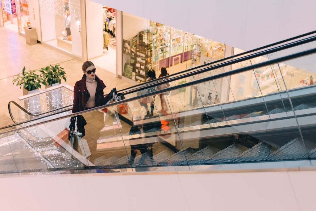 A woman is leading down an escalator in a shopping mall.