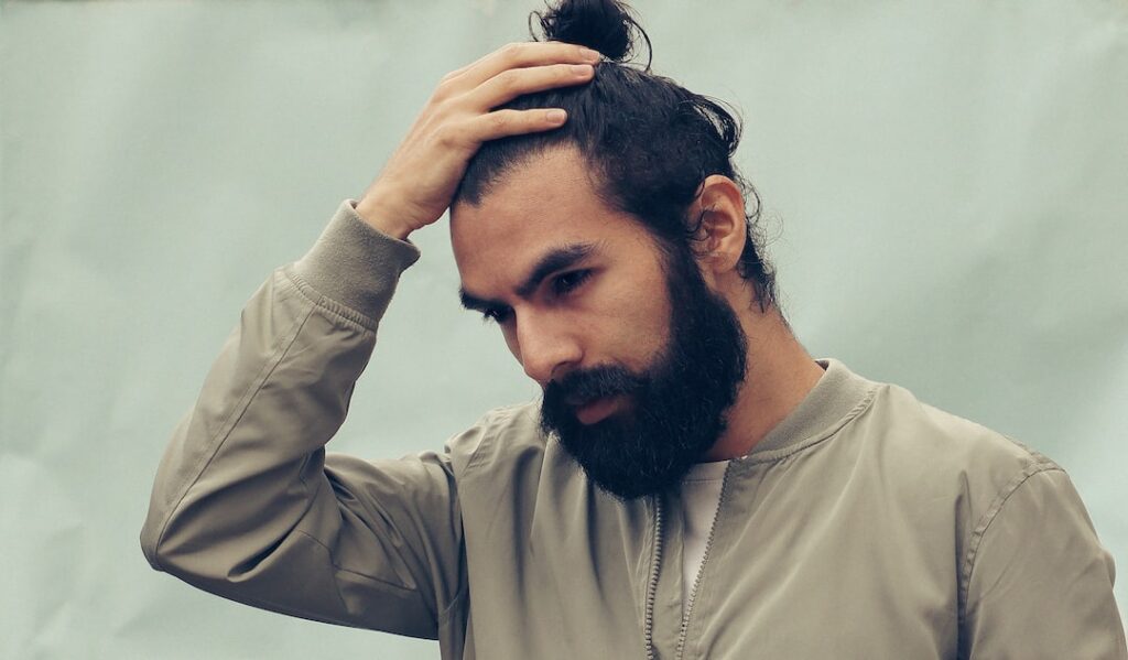 A man with a perfect beard looking at his hair.