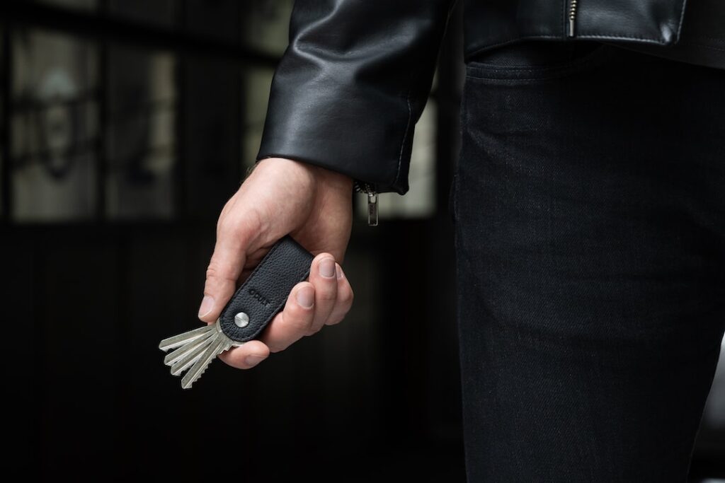 A man in a leather jacket holding an outstanding key.