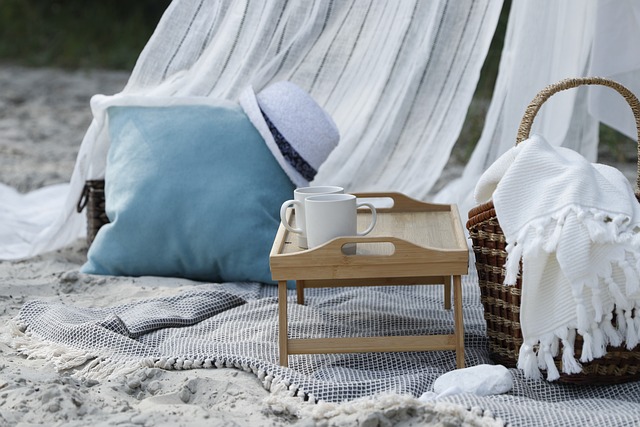 A perfect picnic basket on the beach with a hat and a cup of coffee.