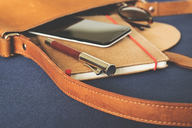 A perfect brown leather bag with a notebook, pen, and phone.