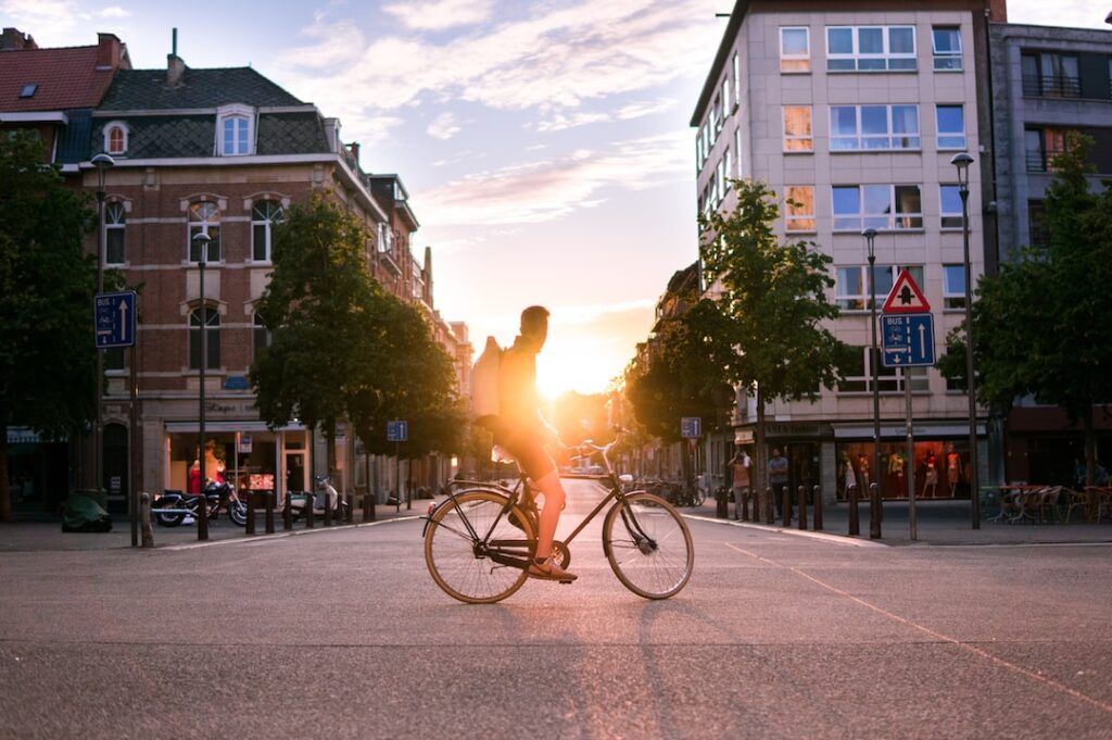 A leading man riding a bicycle on a city street at sunset.