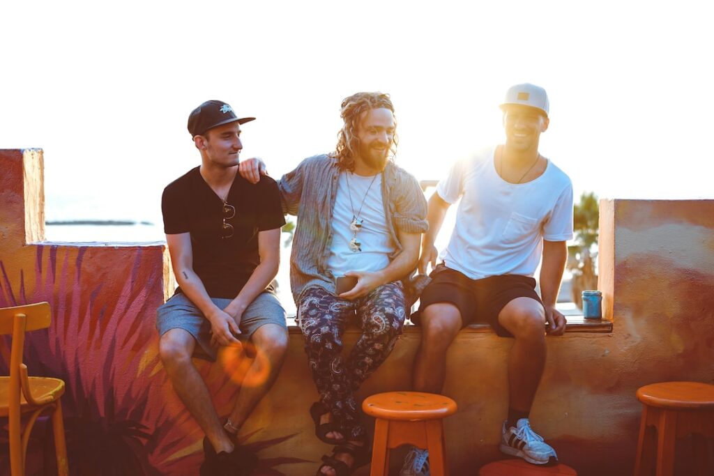 Three men sitting on stools in front of a perfect wall.