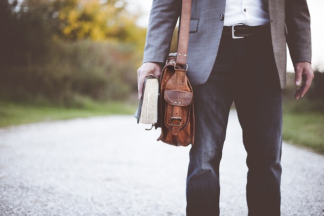 A man walking down a dirt road, holding the finest book.