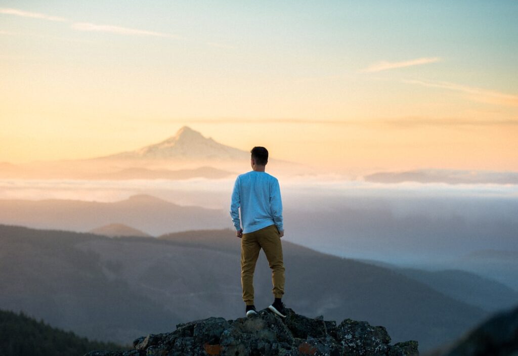 A man enjoying the finest sunset atop a mountain.