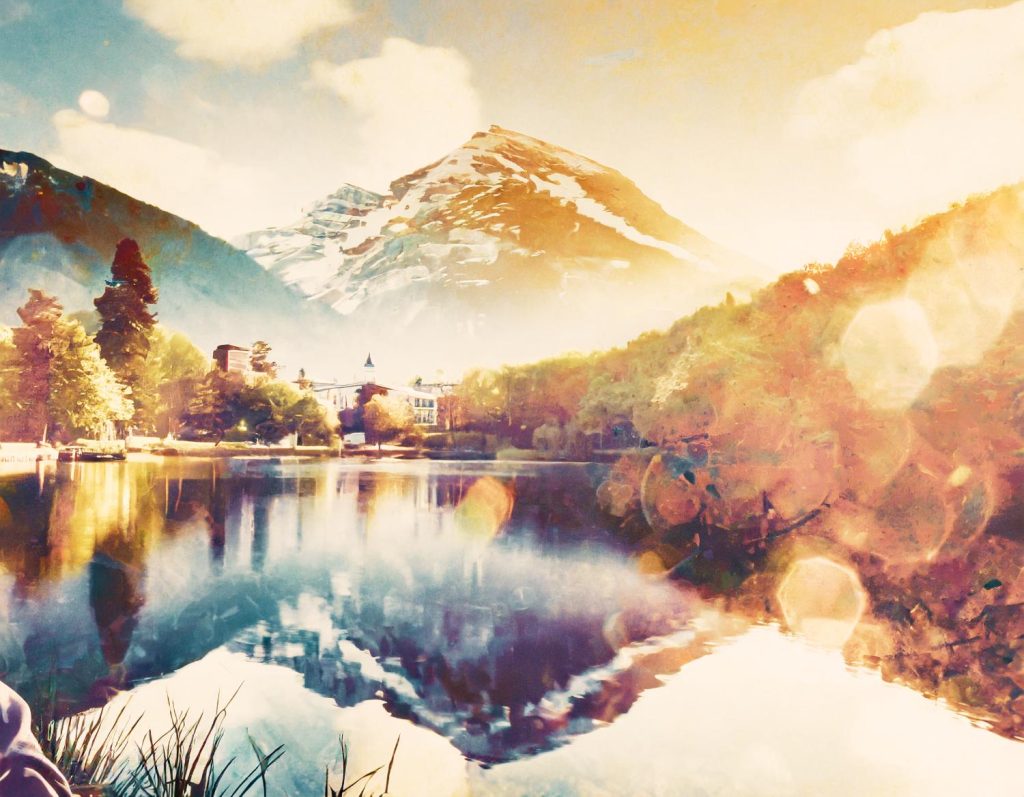 A serene lakeside scene with lush hills, a snow-capped mountain, and a grand building under golden sunlight; nature's timeless elegance reflected.