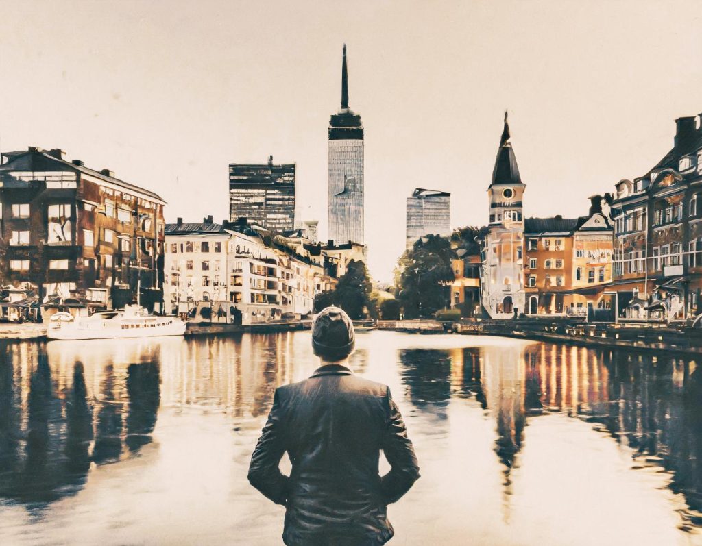 An elegant figure in a suit and hat gazes at a cityscape, blending modern skyscrapers with historic charm. Stylish canvas belt accents the look.
