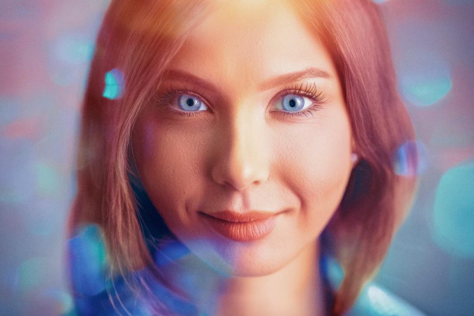 A close-up of a woman with light blue eyes and straight brown hair, smiling gently. Soft, ethereal glow and bokeh lights evoke dreamy elegance akin to the Incase A.R.C. Collection's style.