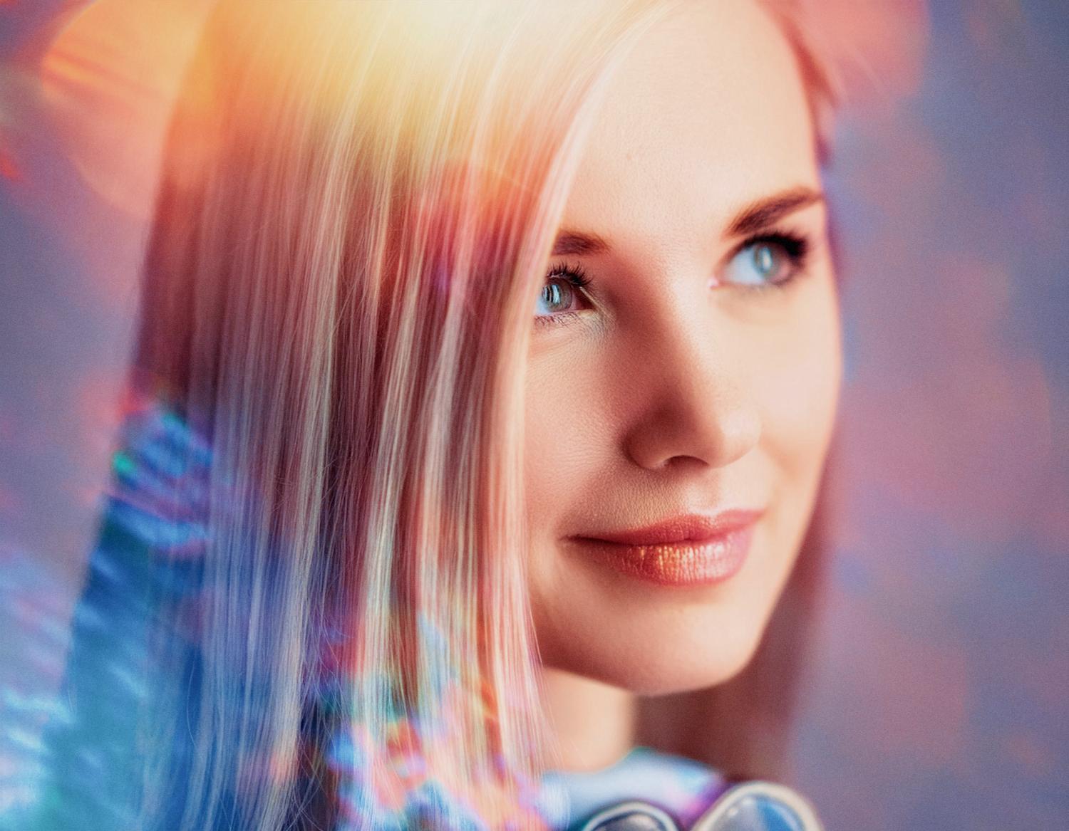 A blonde woman with soft blue eyes smiles gently. She sports a trendy Herschel Supply Roll Top Backpack and stylish headphones, surrounded by dreamy, colorful light effects.