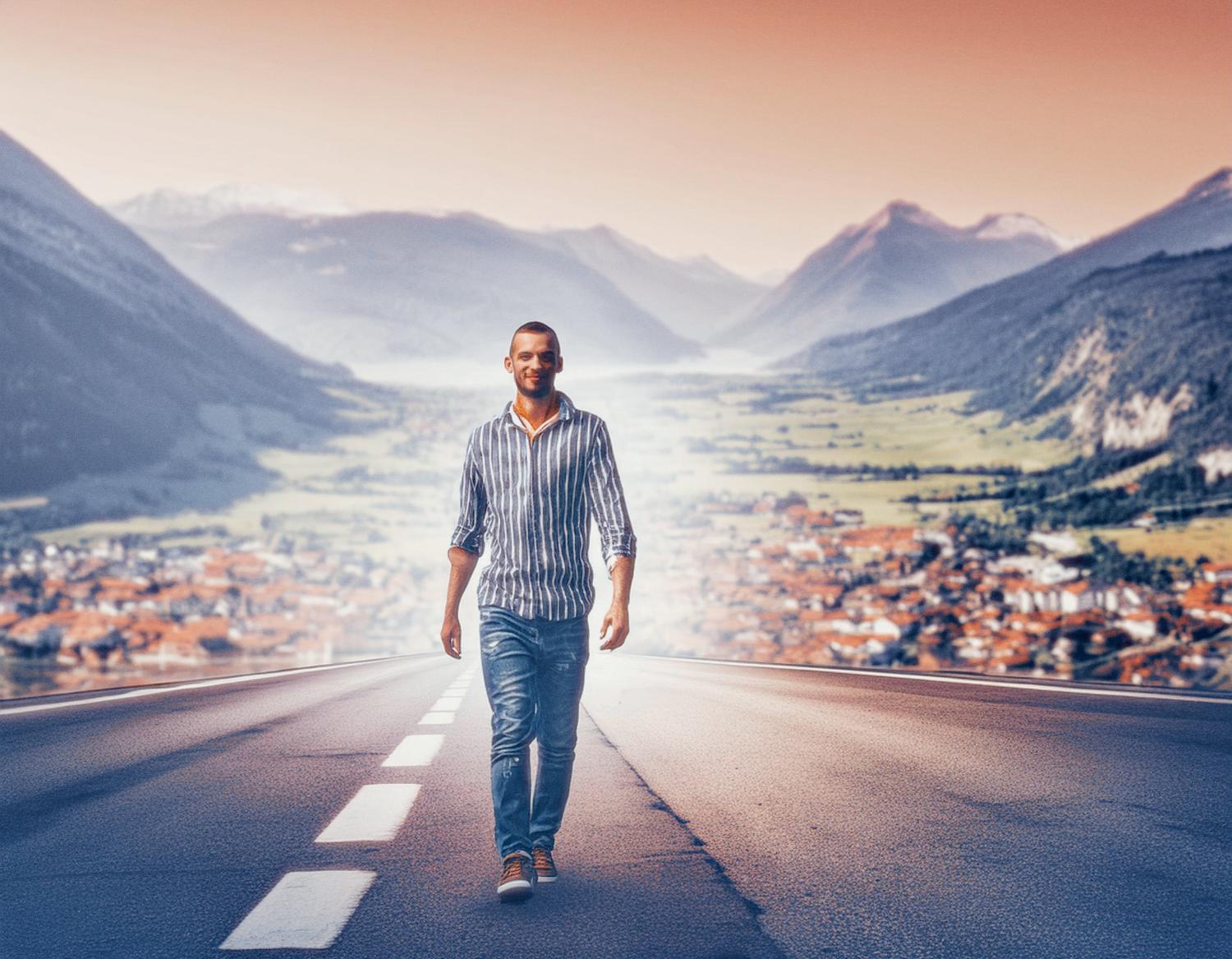 A man in a striped shirt and jeans strides confidently down the road, with a stylish JanSport Pro Crossbody Bag. A picturesque valley town and mountains under a warm skyline create a surreal backdrop, making him appear larger than life.