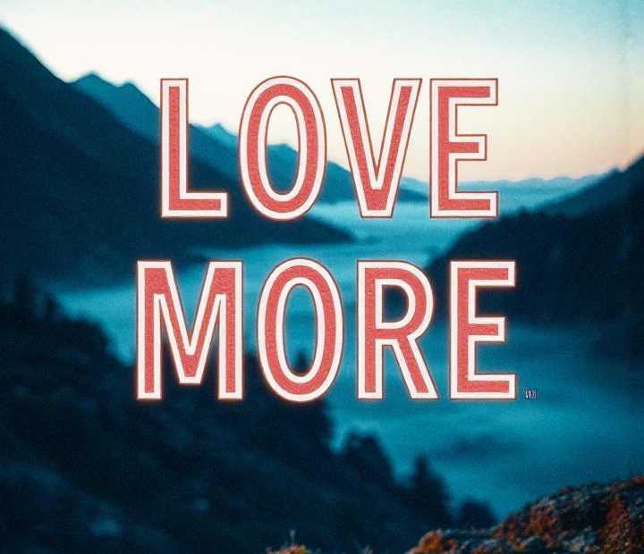 A "LOVE MORE" message glows boldly against a serene mountain dusk. Embrace nature-inspired fashion for an enchanting style statement.